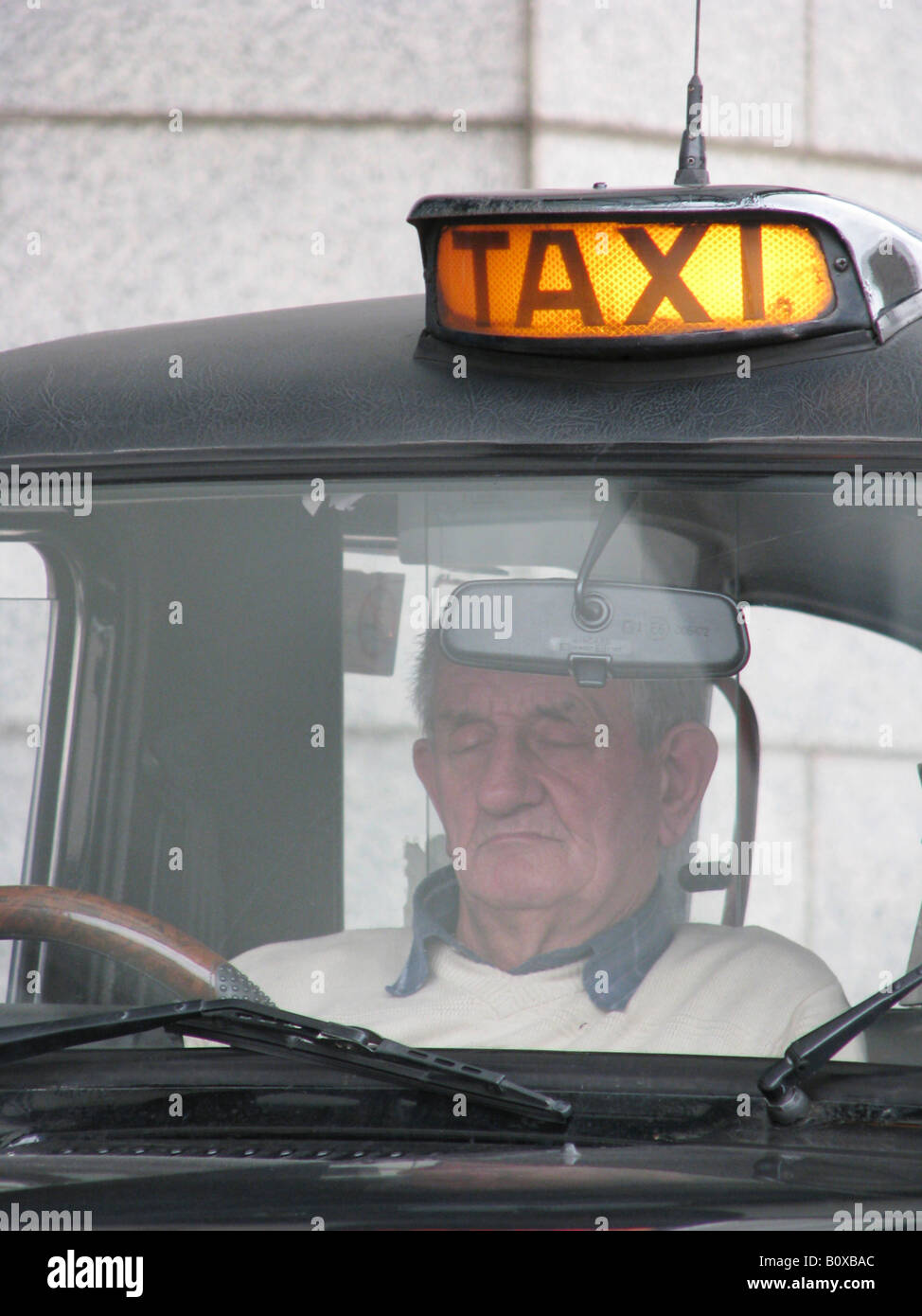 Old black English taxi with illuminated figures - driver dozing and ...