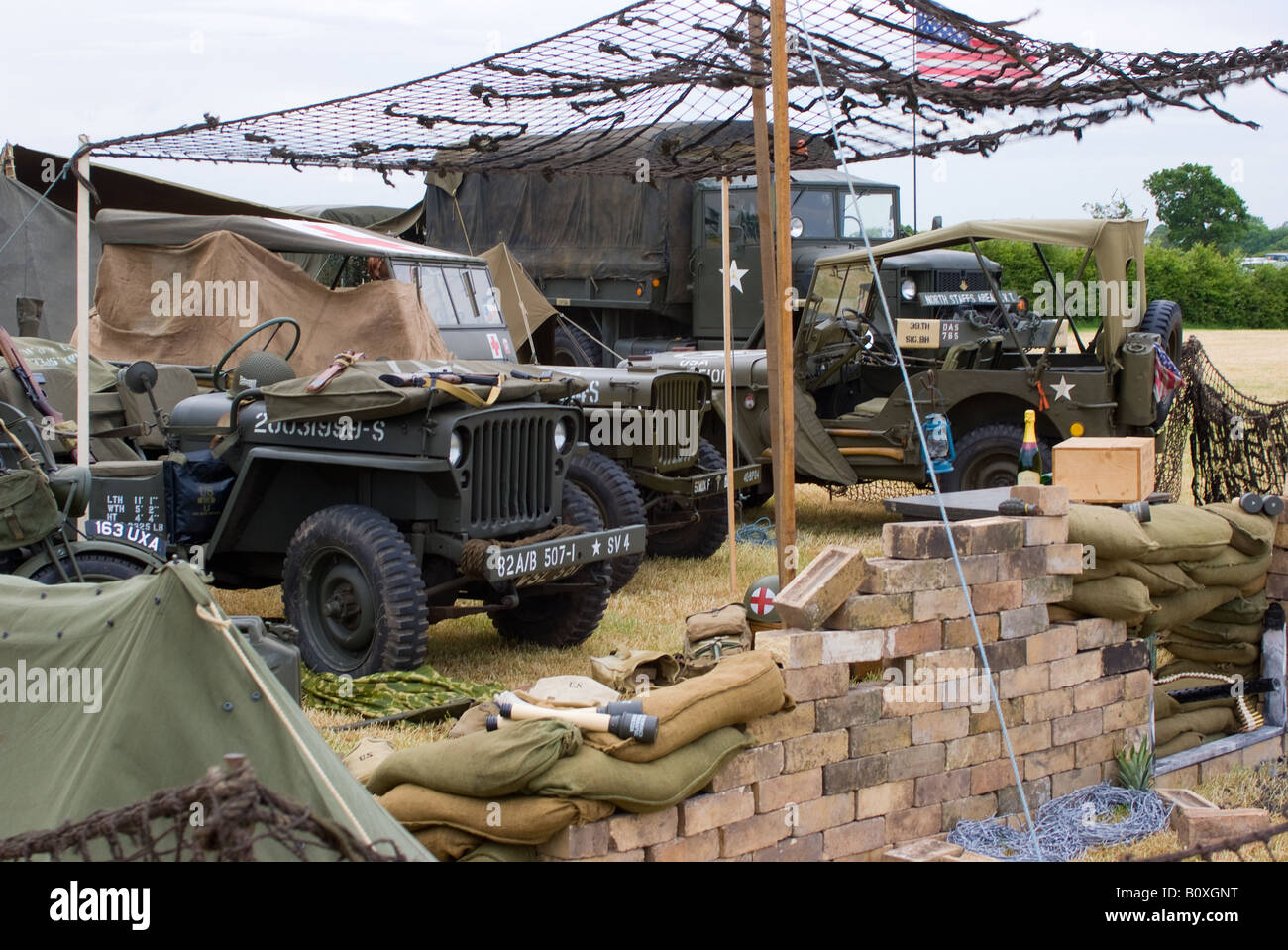 Three United States Army Jeeps and a Reo M35 Truck at Camouflaged Camp at Smallwood Vintage Rally Cheshire England UK Stock Photo