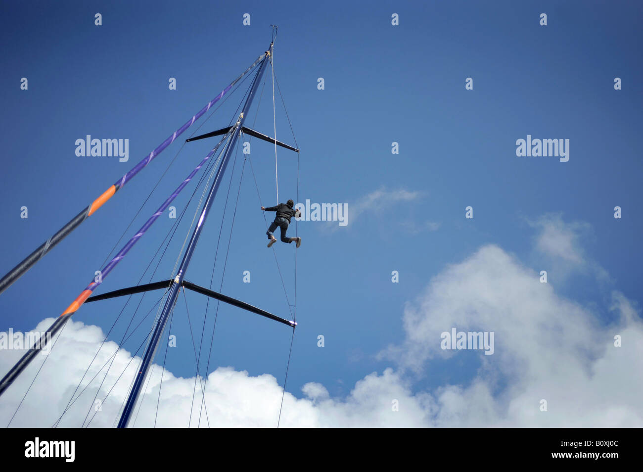 A man sailor climbing up the mast of a racing yacht, pictured in Plymouth, Devon. Stock Photo