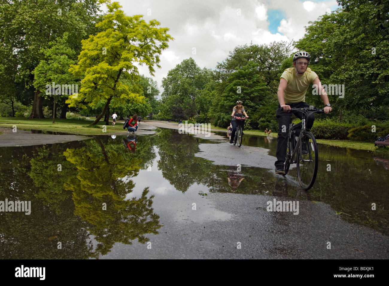 cyclists going through a puddle in victoria park london Stock Photo