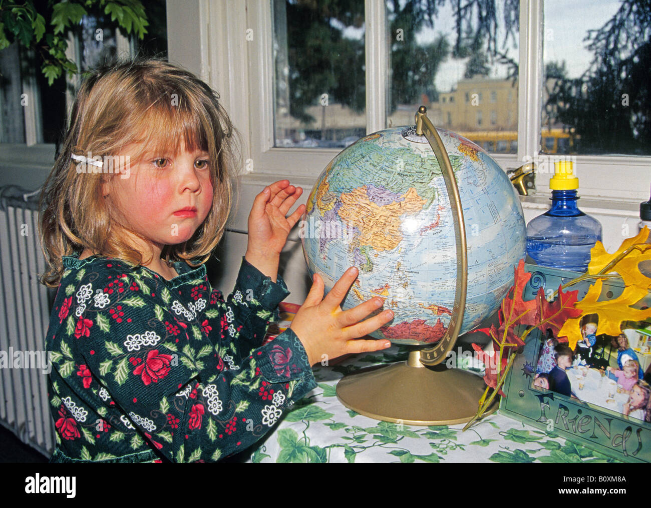 A four year old preschool student examines a globe map of the world at
