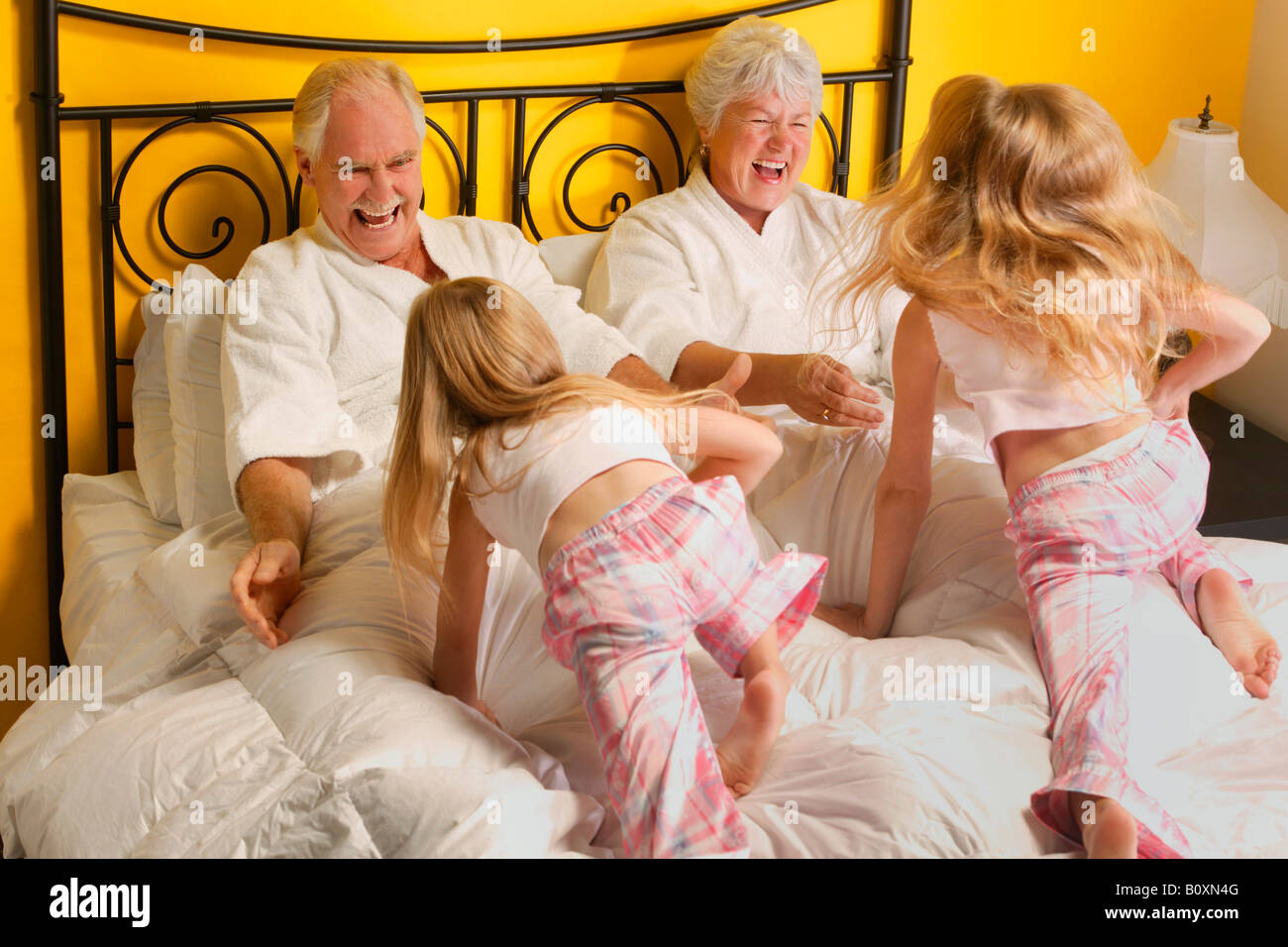 Grandparents playing with their granddaughters in a bed Stock Photo Alamy