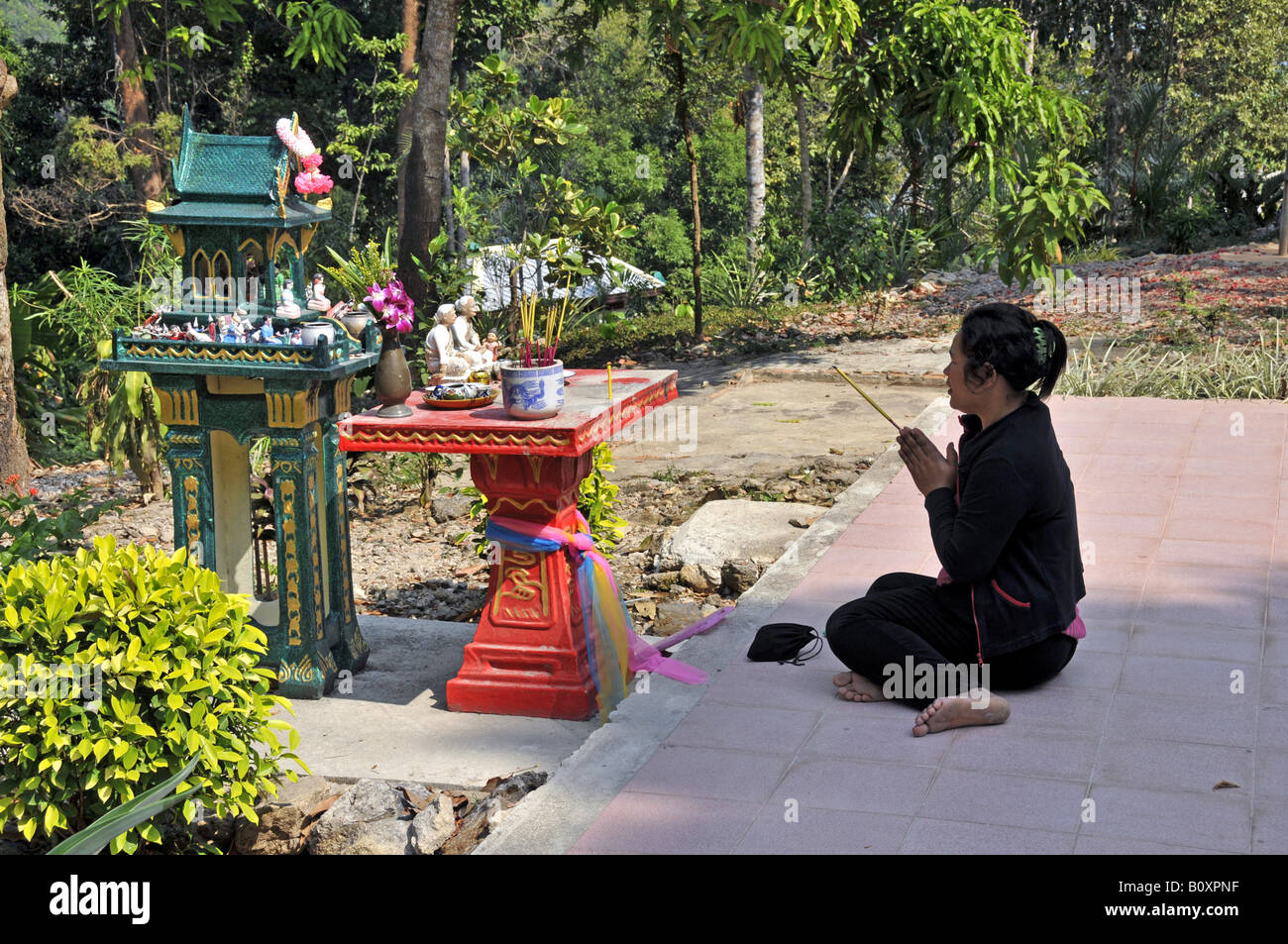 woman praying in front of a ghost house, Thailand, Koh Chang Stock Photo