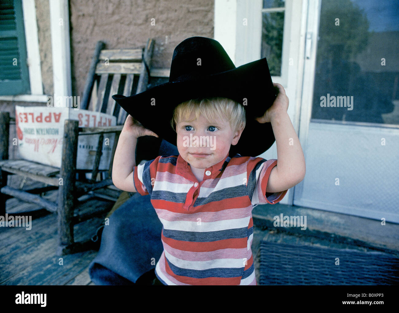 A young cowboy guest on the porch of the bunkhouse on a dude ranch near Lincoln New Mexico Stock Photo