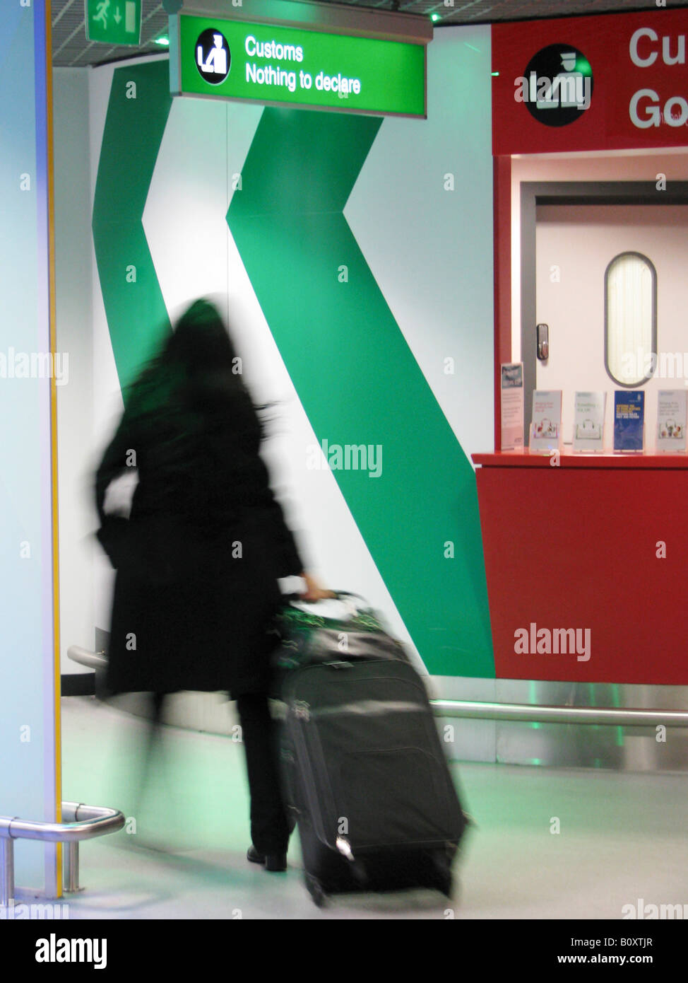 Female traveller passing an illuminated sign at the airport showing a symbol of the customs -  'Nothing to declare', United Kin Stock Photo