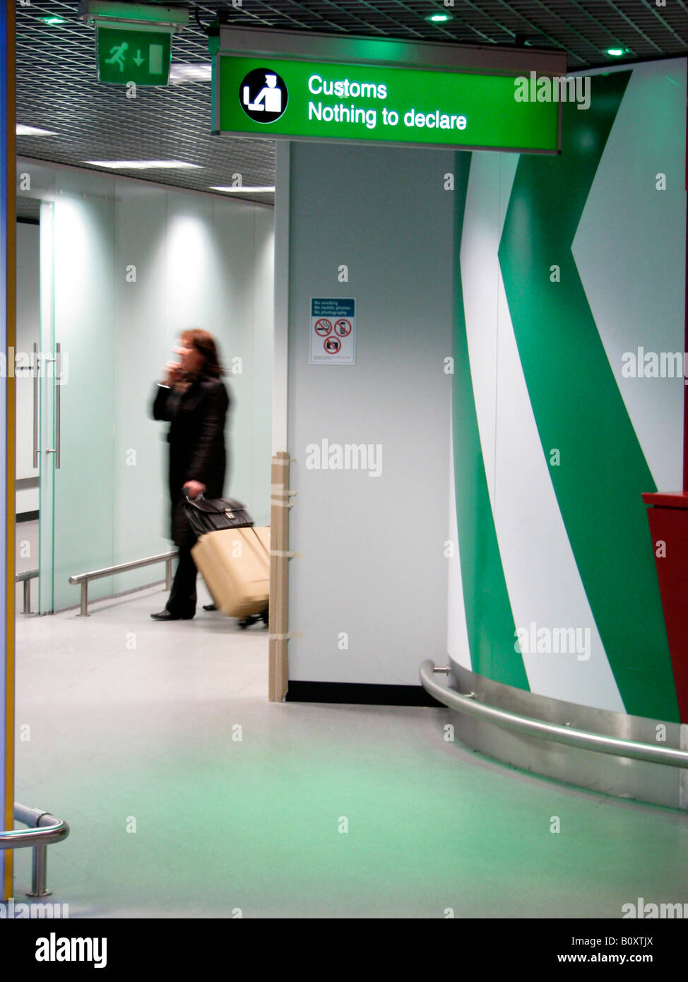 Female traveller passing an illuminated sign at the airport showing a symbol of the customs -  'Nothing to declare', United Kin Stock Photo