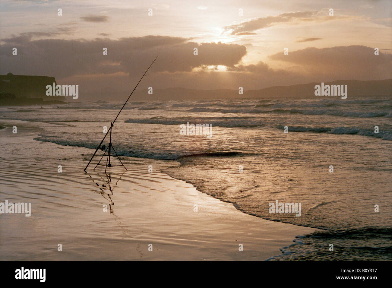 Sea fishing rod on a tripod on a beach with incoming tide at