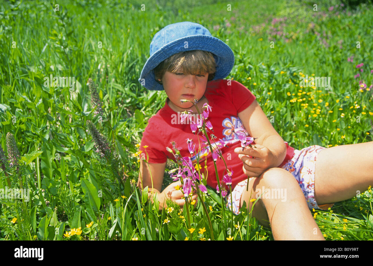 A young girl smells wildflowers in an alpine meadow on Iron Mountain Trail near Bend Stock Photo