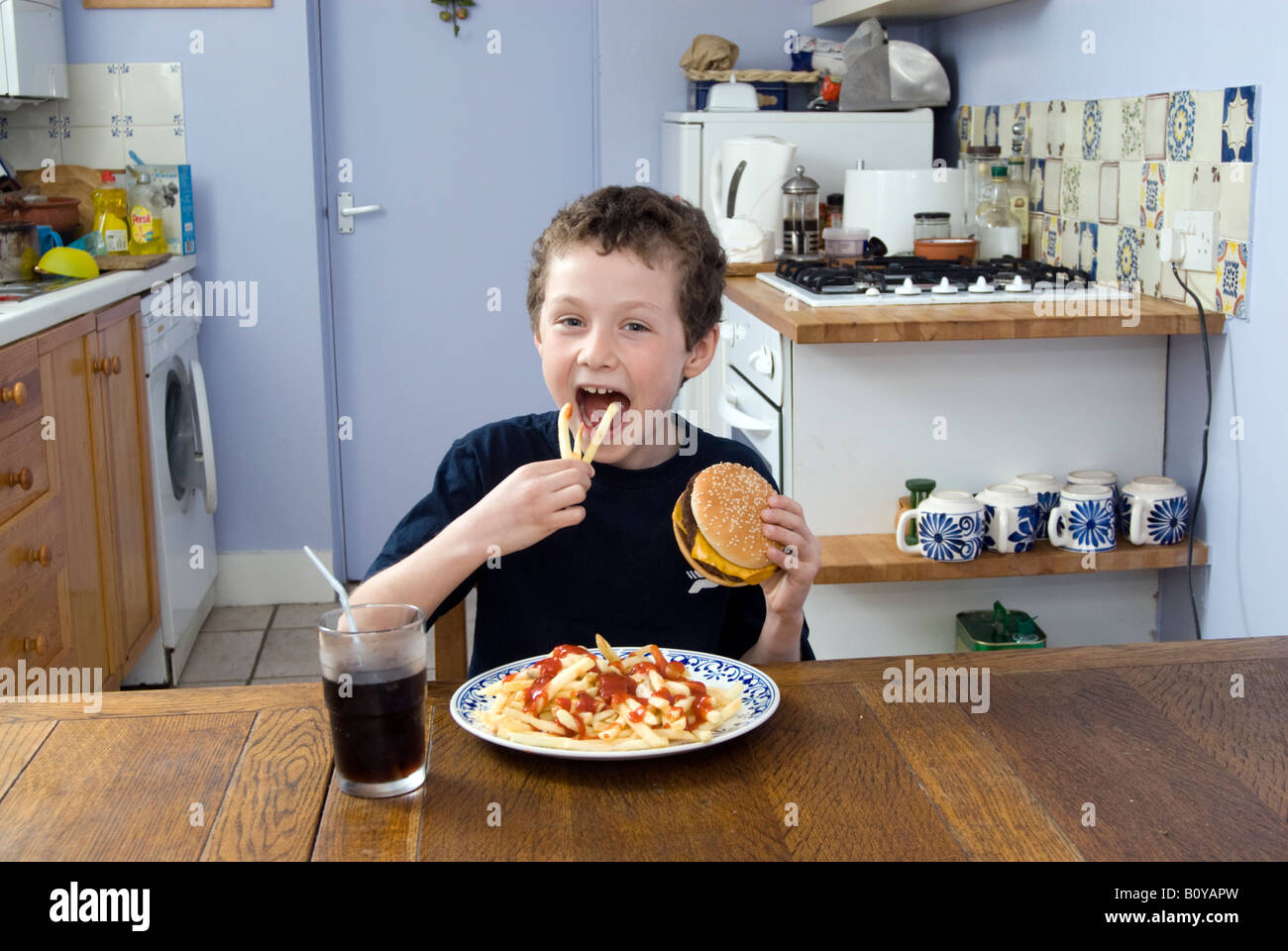 Boy eating junk food at home, England UK Stock Photo