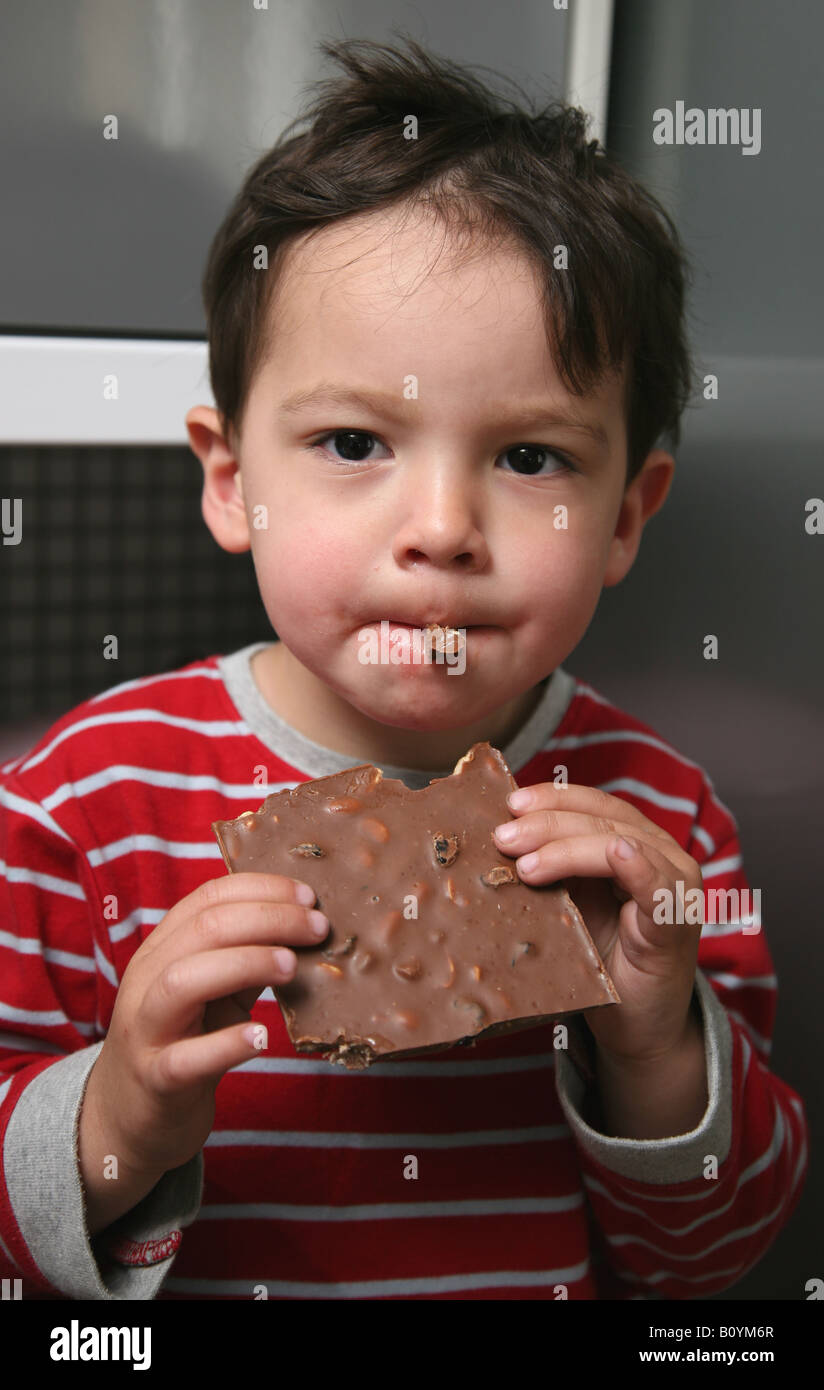Toddler eating a large chocolate bar containing nuts Stock Photo Alamy