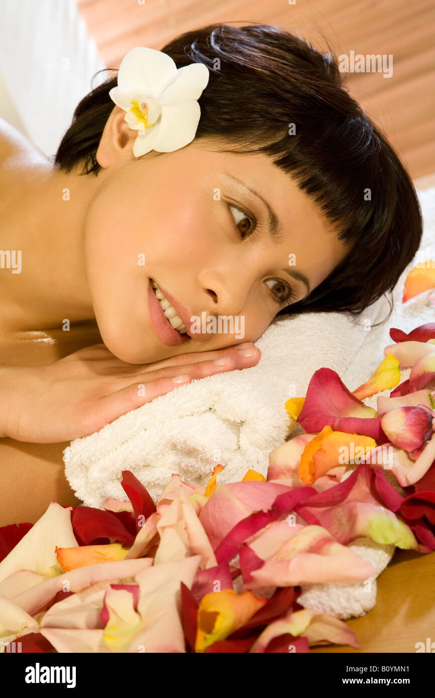 Young woman lying down with rose petals Stock Photo