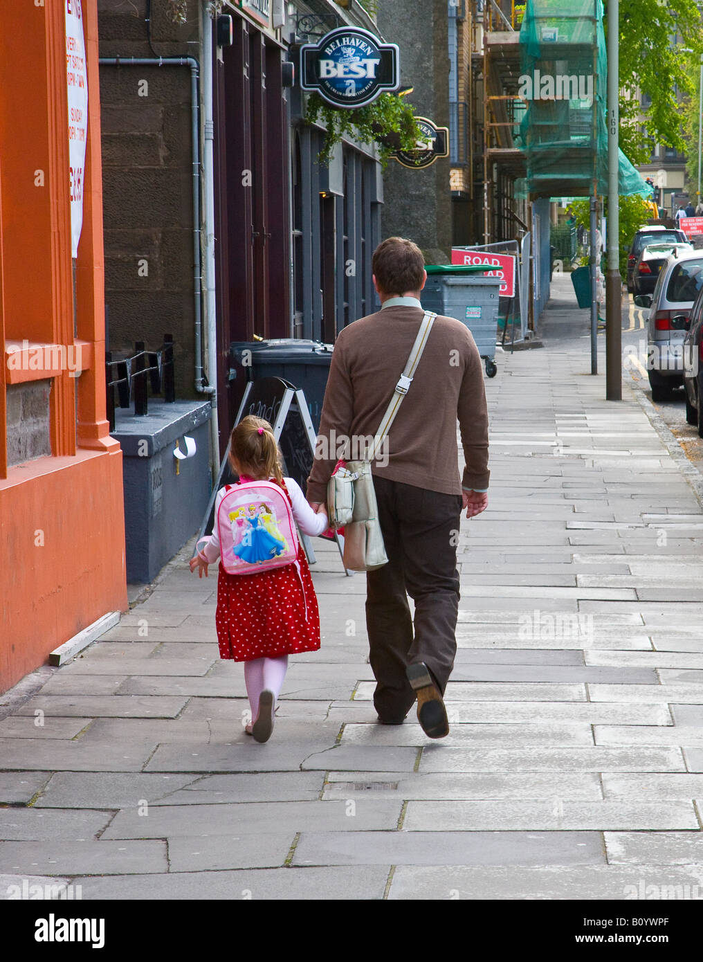 father holding daughters hand as they walk down the street Stock Photo ...