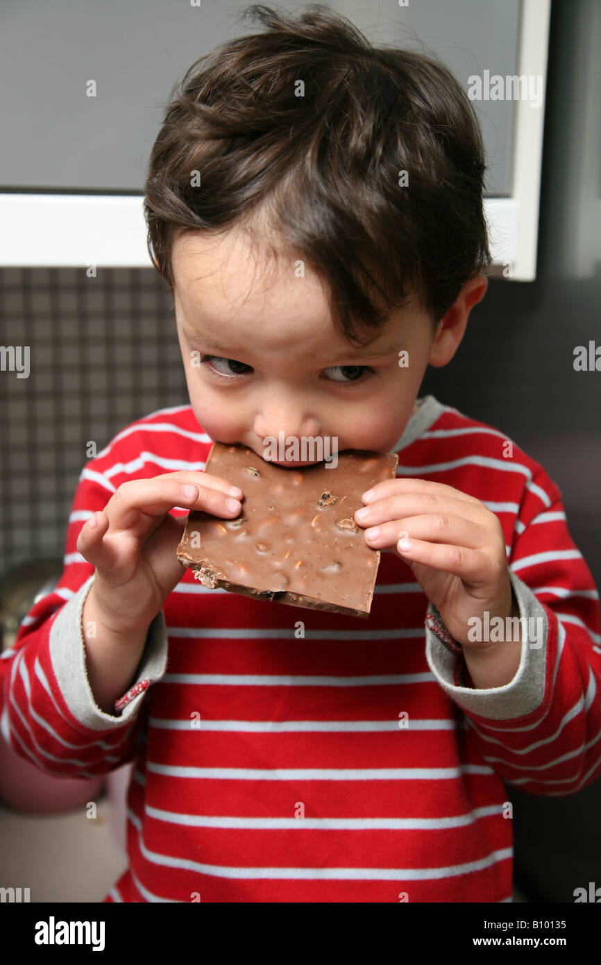 Bad parenting a 3 year old child being aloud to eat a large slab of chocolate Stock Photo