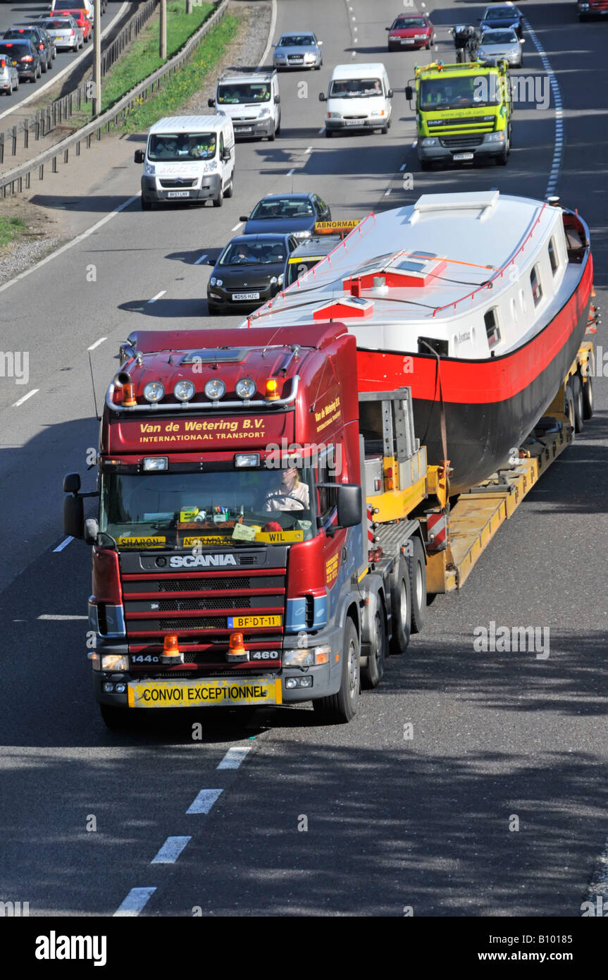 Scania lorry truck driving M25 motorway wide oversized boat load on low loader trailer joining motorway slip road CONVOI EXCEPTIONNEL Essex England UK Stock Photo
