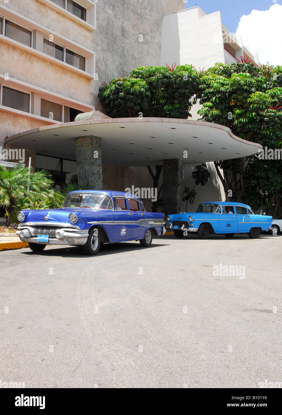 Havana, Cuba. 2 classic American cars wait outside the Comodoro Hotel in the Mirimar district. 1955 Chevrolet and Pontiac Stock Photo