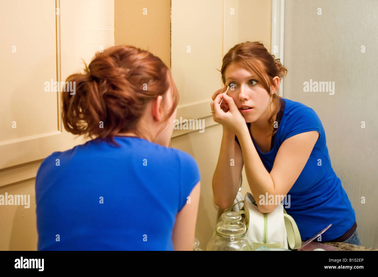Young woman in a bathroom doing her makeup Stock Photo