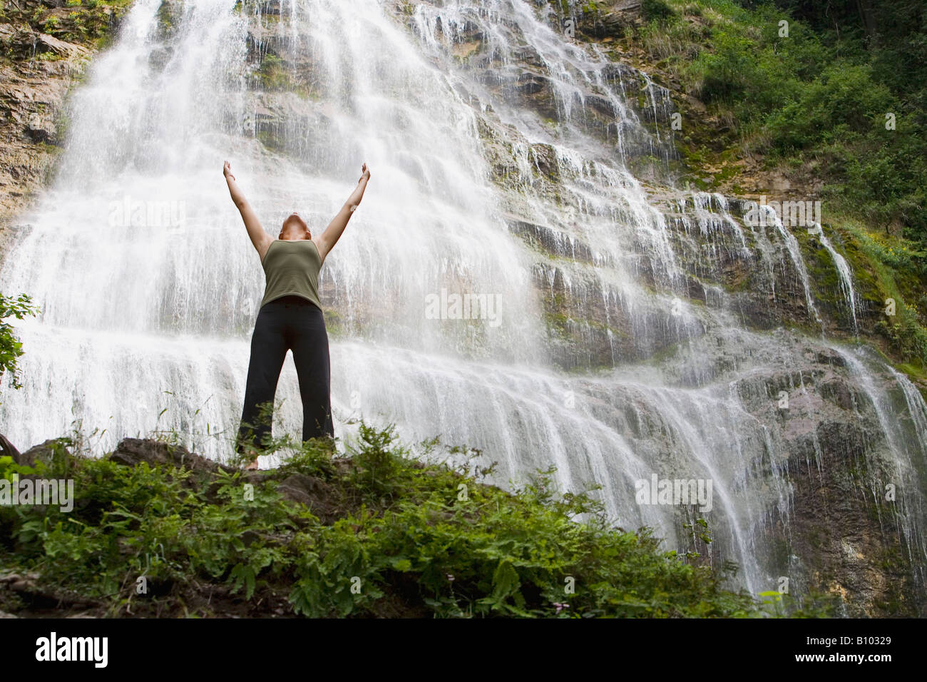 Woman with her arms raised in front of waterfall Stock Photo - Alamy