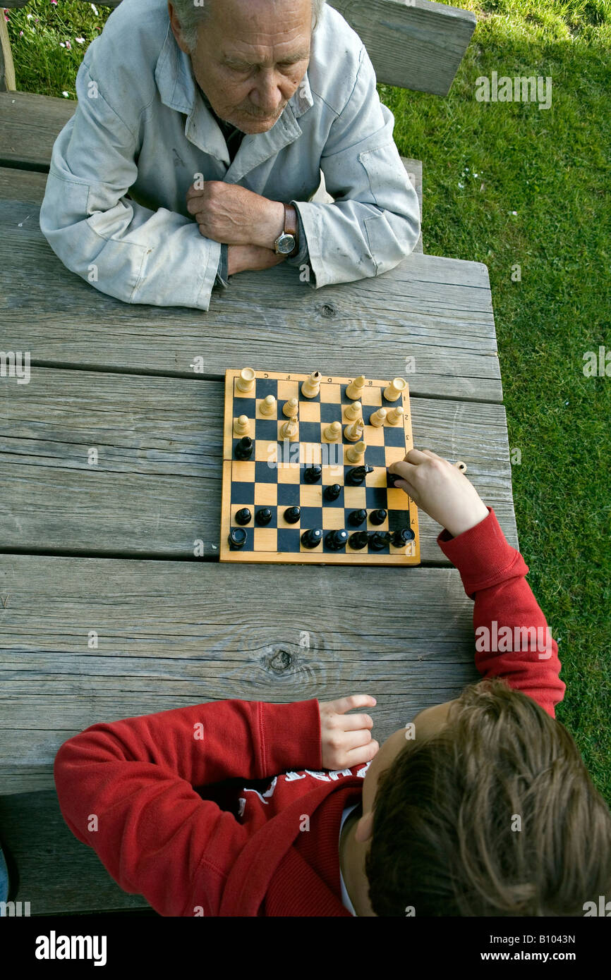 Grandfather and boy playing game of chess in the garden Stock Photo