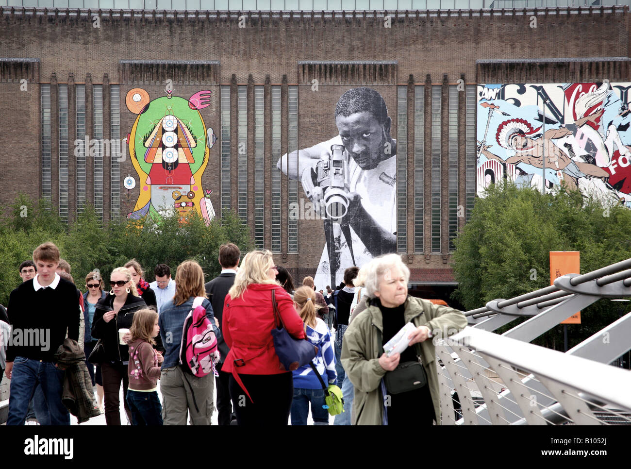 Giant street art figures on Tate Modern in London dominate pedestrians on the Millennium footbridge Stock Photo