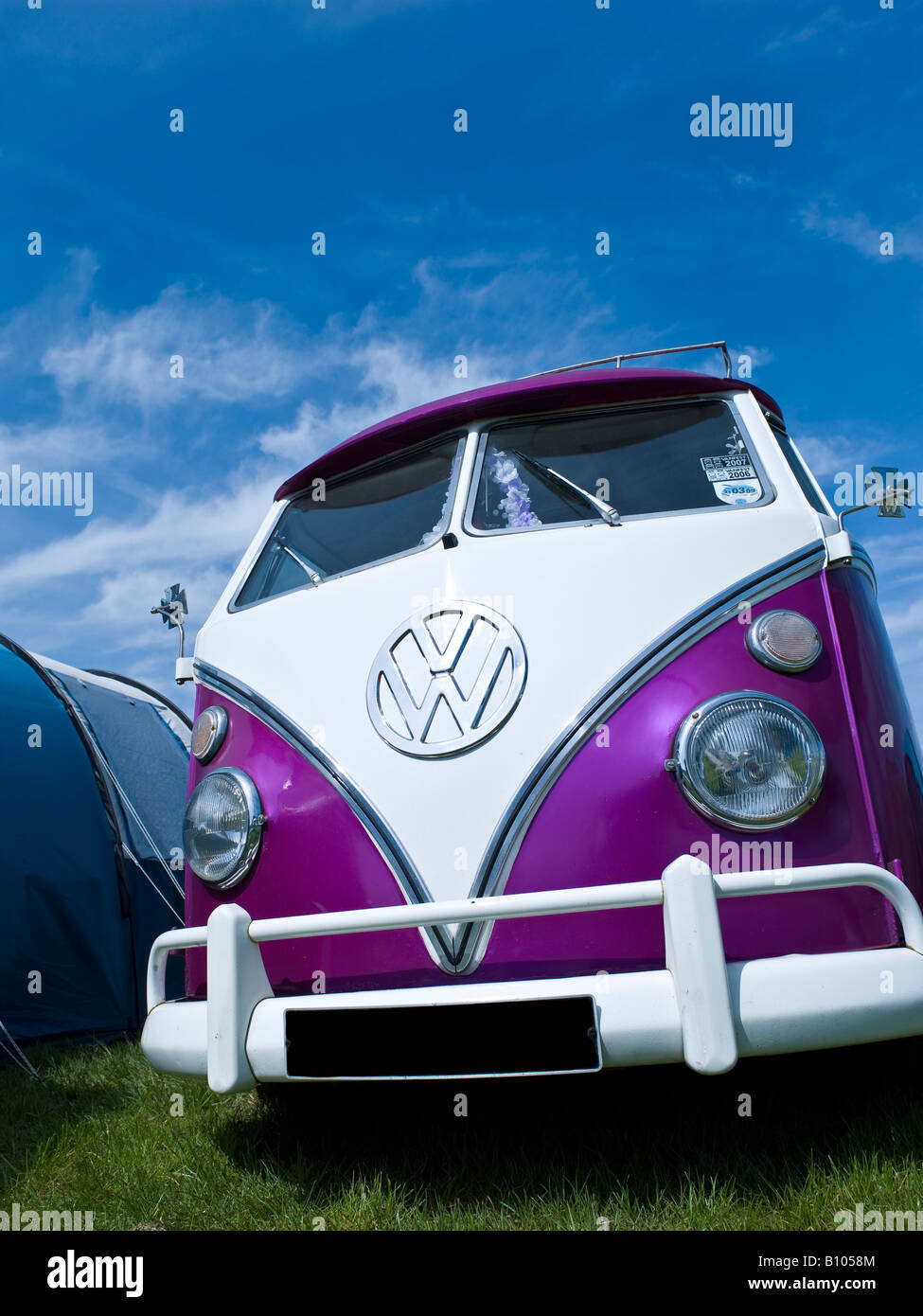vw volkswagen split screen bus camper van with blue summer sky on a field with a tent Stock Photo