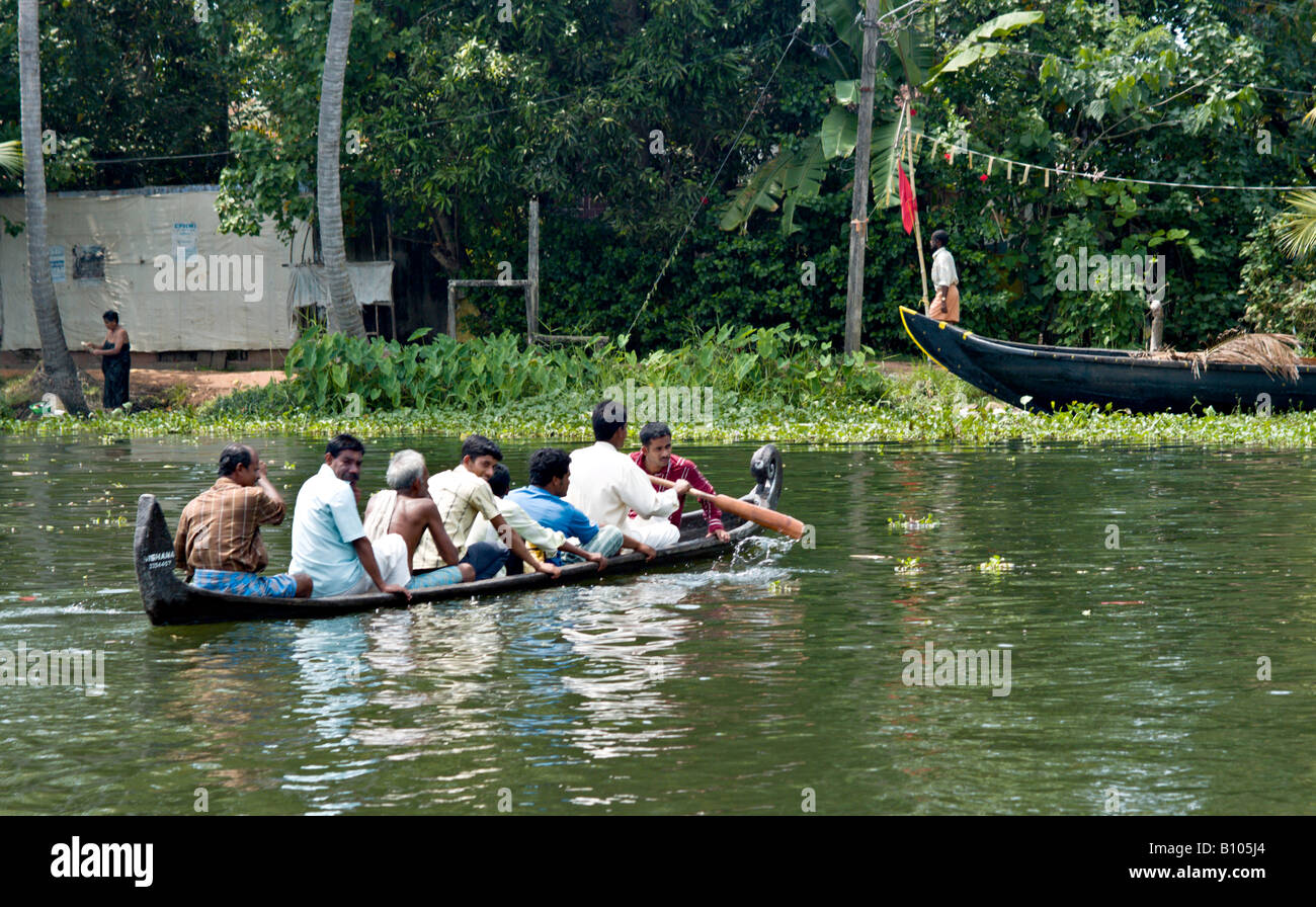 INDIA KERALA Overloaded canoe of eight Indian men rowing across the