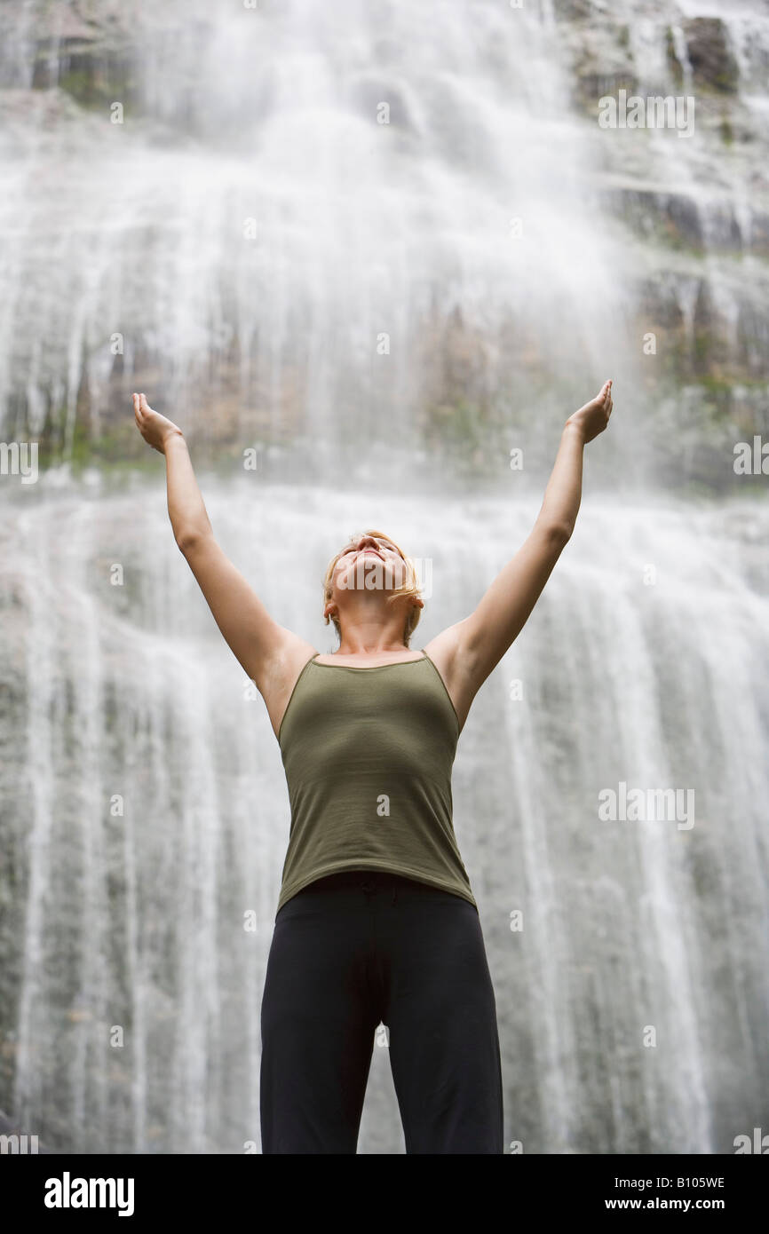 Woman with arms raised in front of waterfall Stock Photo - Alamy