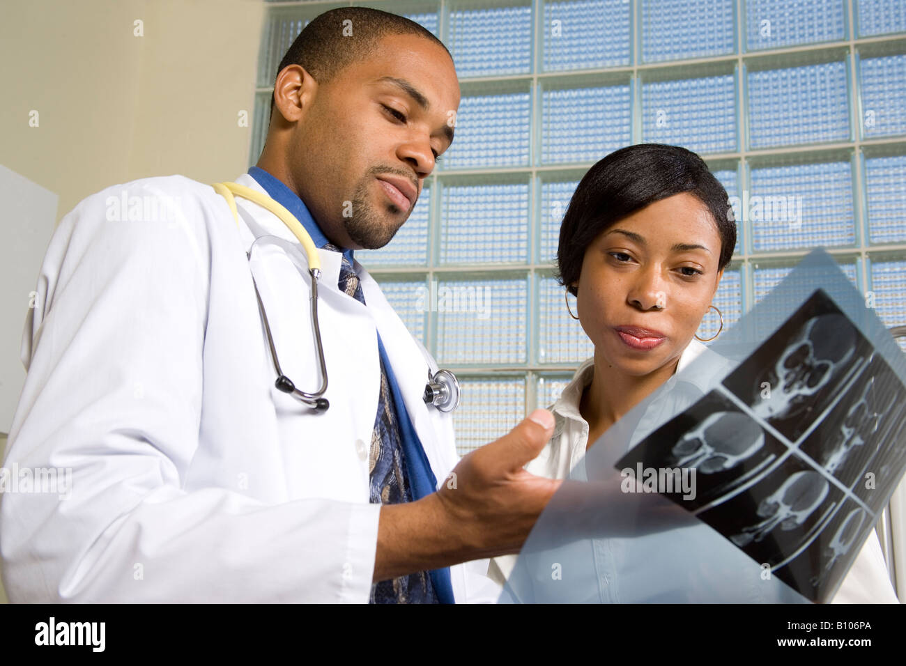 Black doctor shows female patient x-ray Stock Photo - Alamy