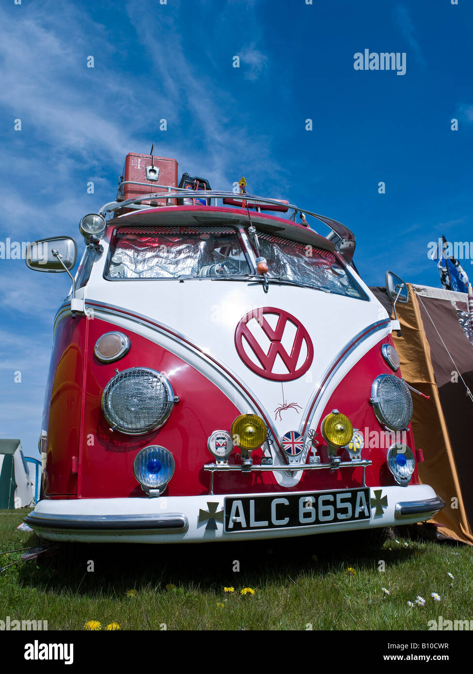 vw volkswagen split screen bus camper van variant bug beetle engine lowered red hippie hippy 1960s in a field camping Stock Photo