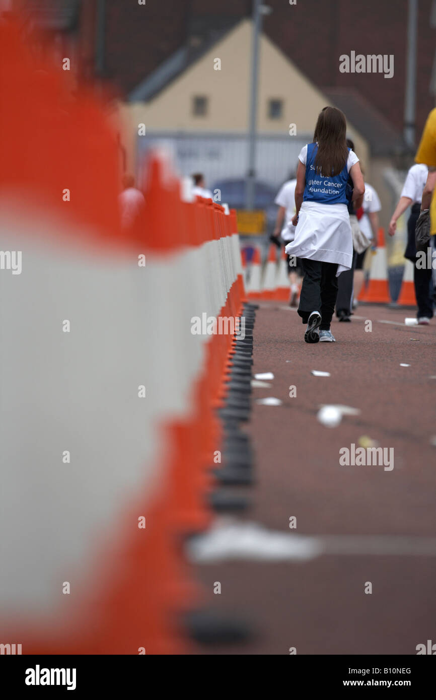 female competitor walks past line of traffic cones being used to cordon off marathon route Stock Photo