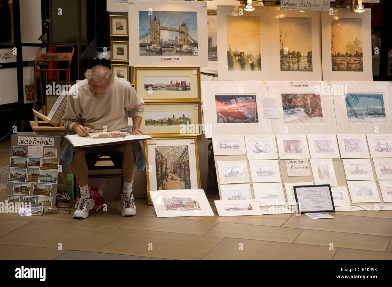 Street artist painting and selling fine art paintings in Hay's Galleria London UK Stock Photo