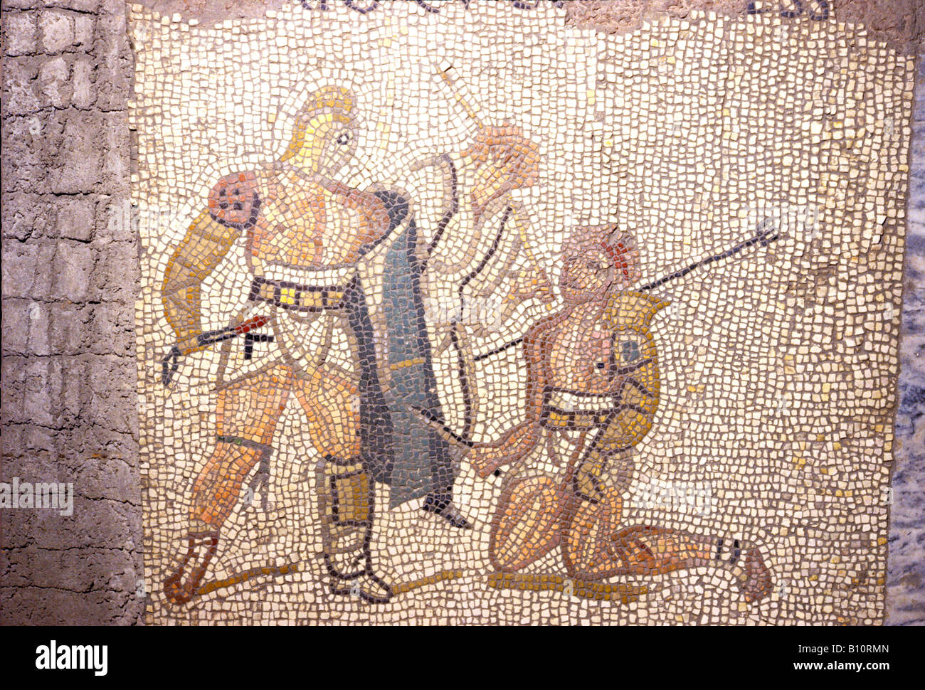 Roman mosaic, Gladiators defeated Retarius kneels, Umpire behind. Stock Photo