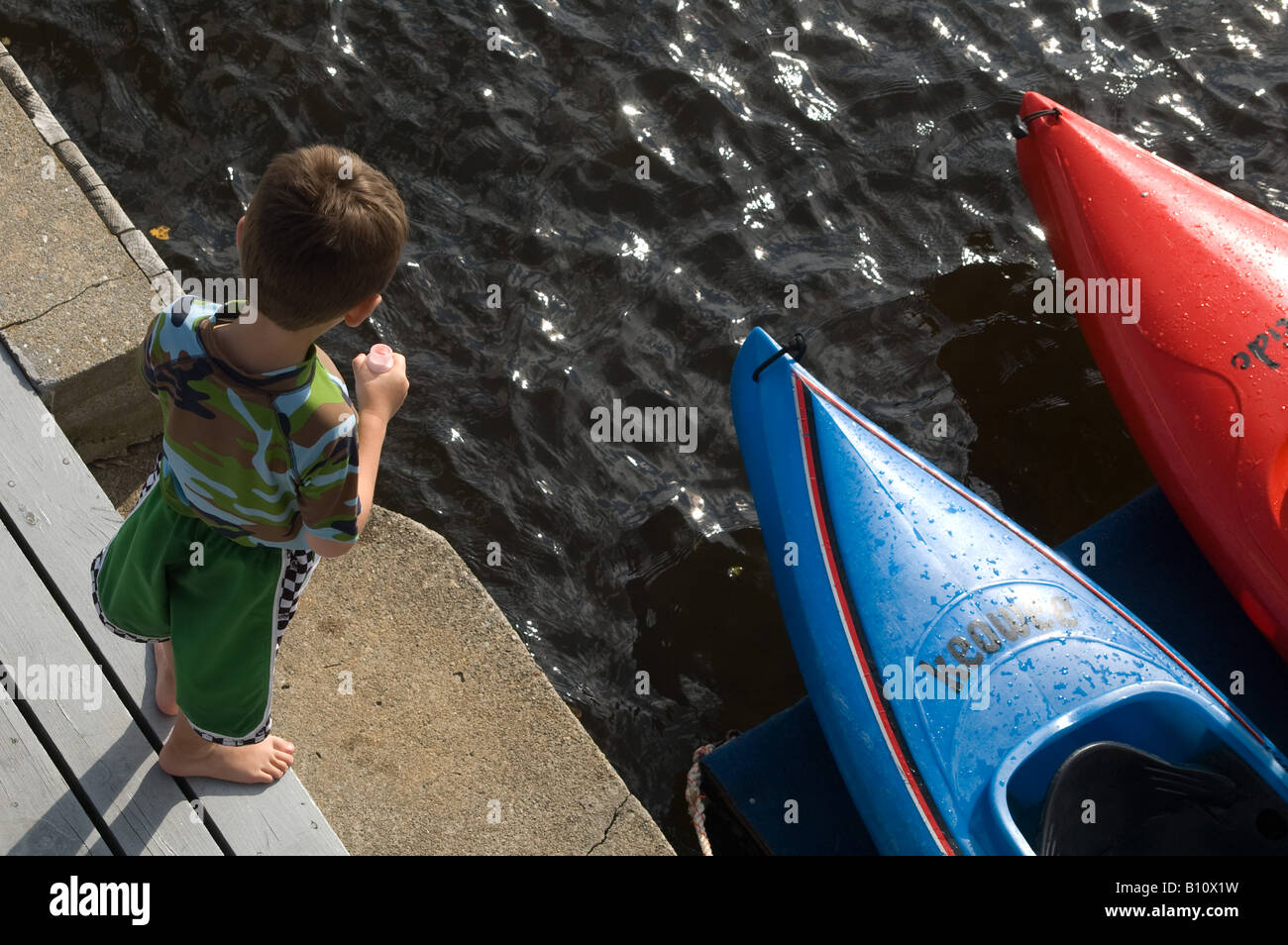 overhead view young boy on boat dock colorful kayaks Stock Photo