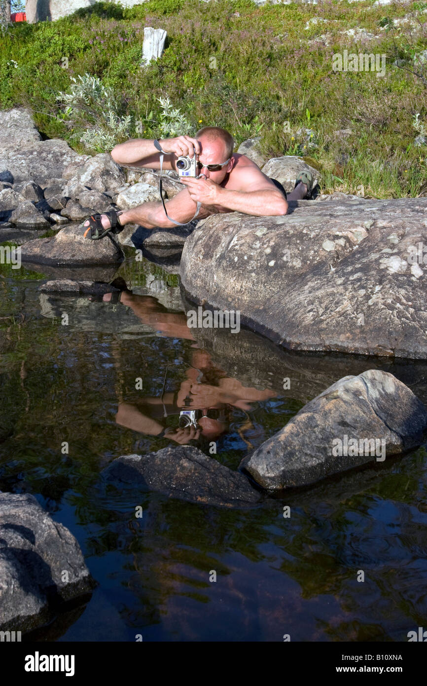 Man taking a photograph reflected in water on Istren lake, Femundsmarken, Ostfold, Norway Stock Photo