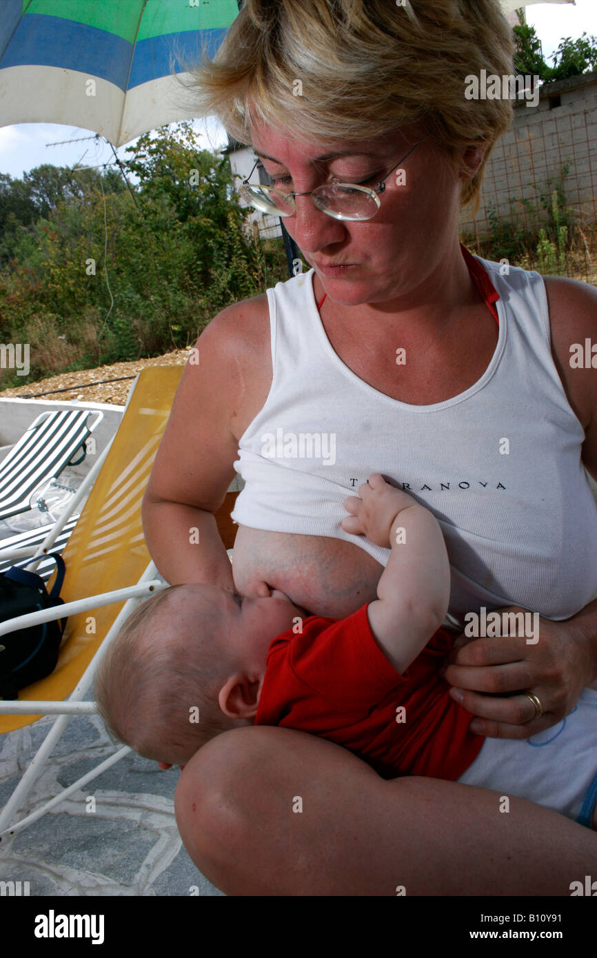 Newborn sucks on mother's bosom Stock Photo