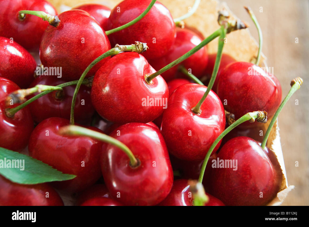 Paper bag full of red cherries on wooden background Stock Photo