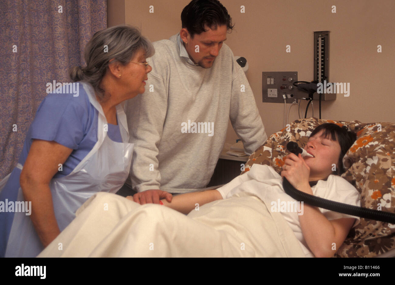 midwife partner supporting young woman in labour using gas air for pain relief Stock Photo