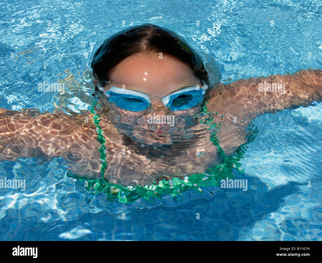 A girl emerges from the water while swimming in a backyard pool in