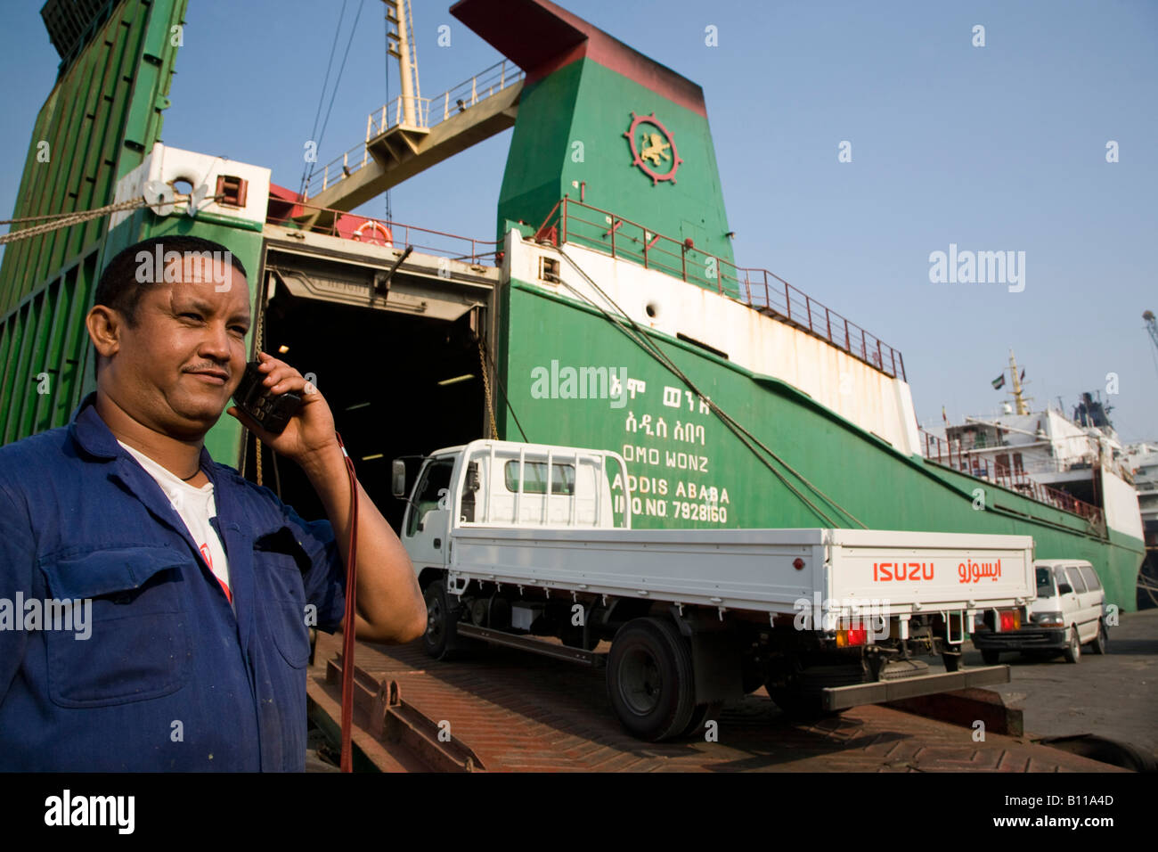 Stevedore overseeing loading operations as lorries are loaded onto a carship at Port Khalid United Arab Emirates Middle East Stock Photo