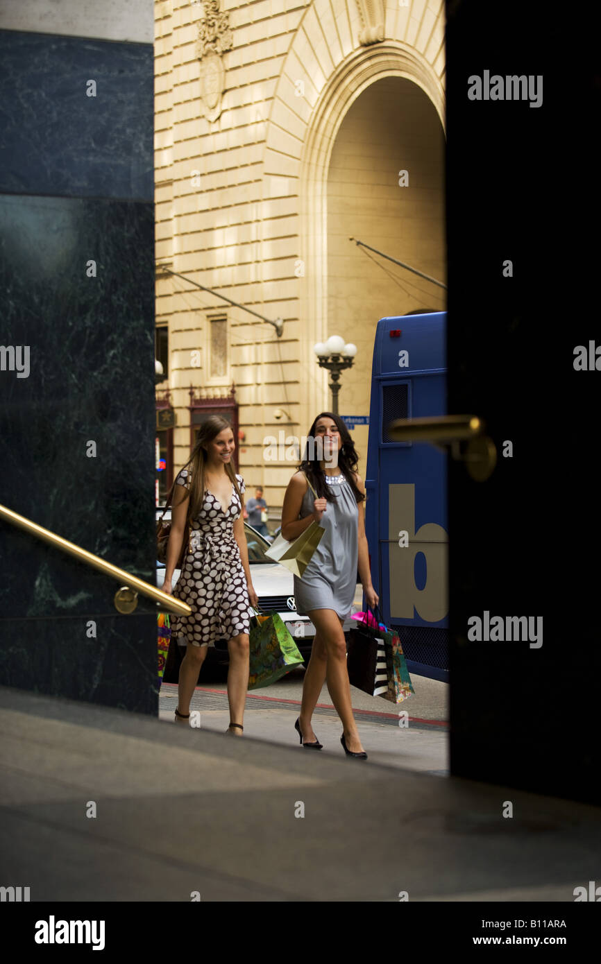 Two young women walking by doorway carrying shopping bags Stock Photo ...