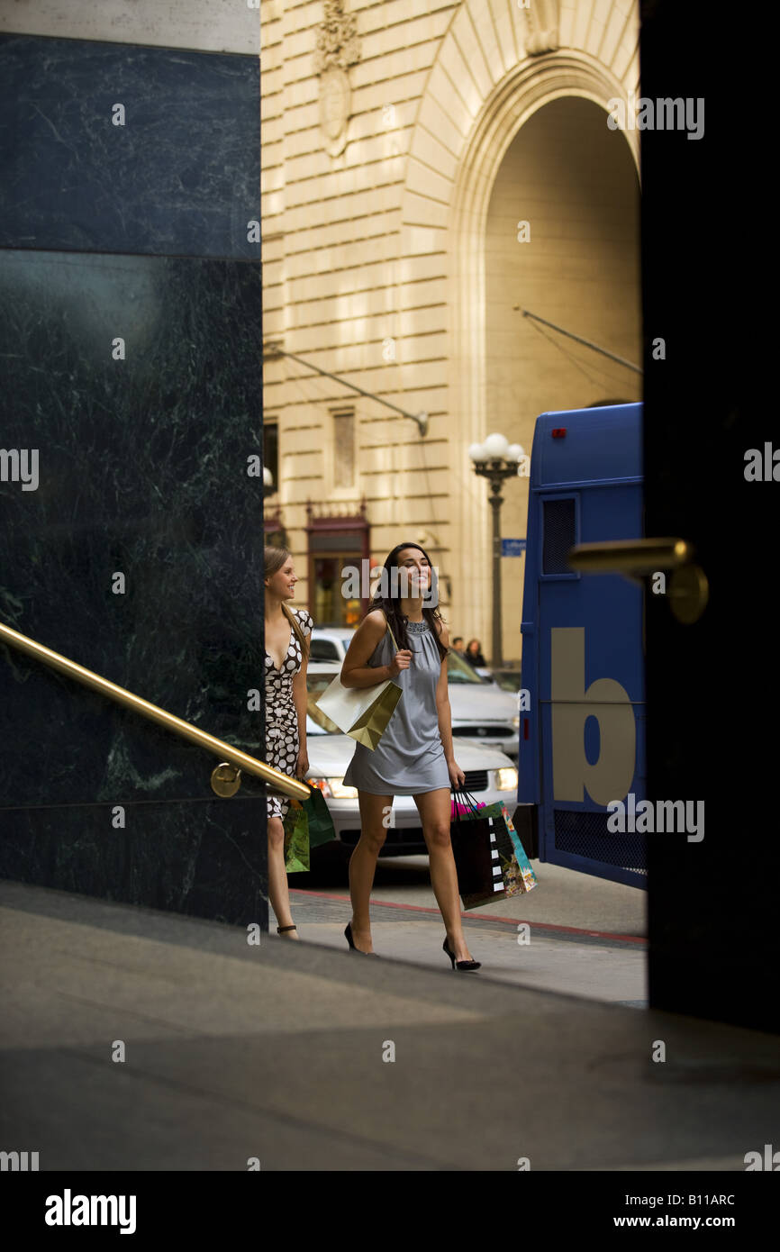 Two young women walking by doorway carrying shopping bags Stock Photo ...