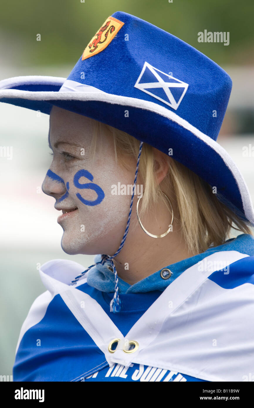 Female football soccer fan in her teams colours blue and white with a cowboy hat on face painted and a flag Scotland UK Stock Photo