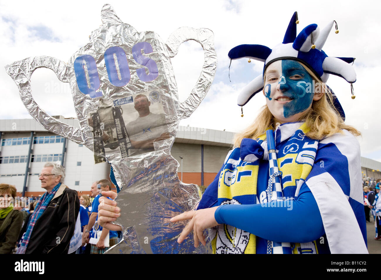 Scottish cup football final female fan supporter with made up cup face painted scarf and flag in teams funny hat Scotland Stock Photo