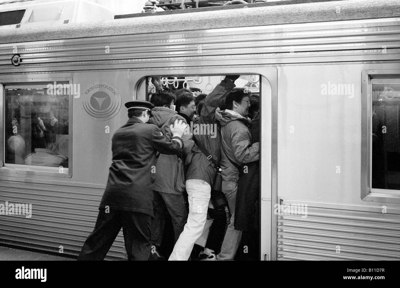 Commuters being pushed into a train travelling from Yokohama to Tokyo at morning rush hour. Stock Photo