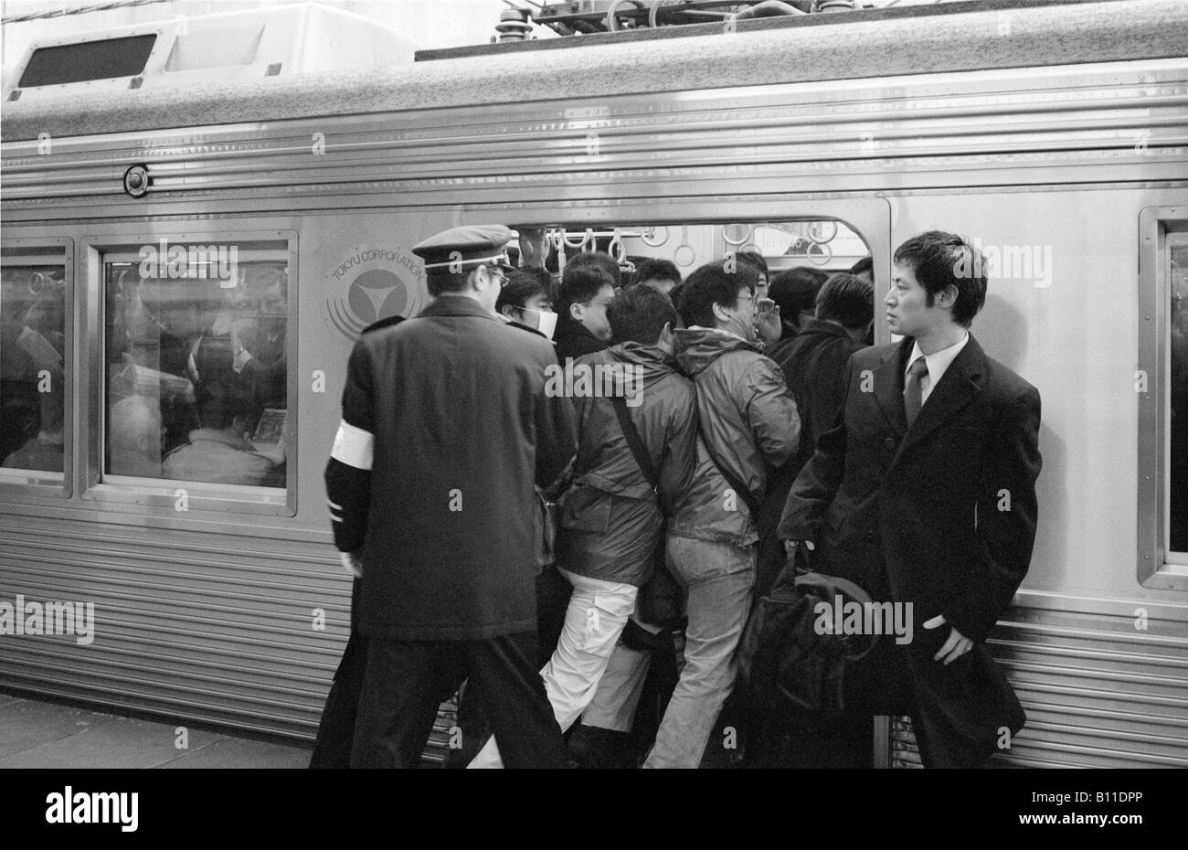 Feb 25, 2004 - Commuters being pushed into a train travelling from Yokohama to Tokyo at morning rush hour. Stock Photo
