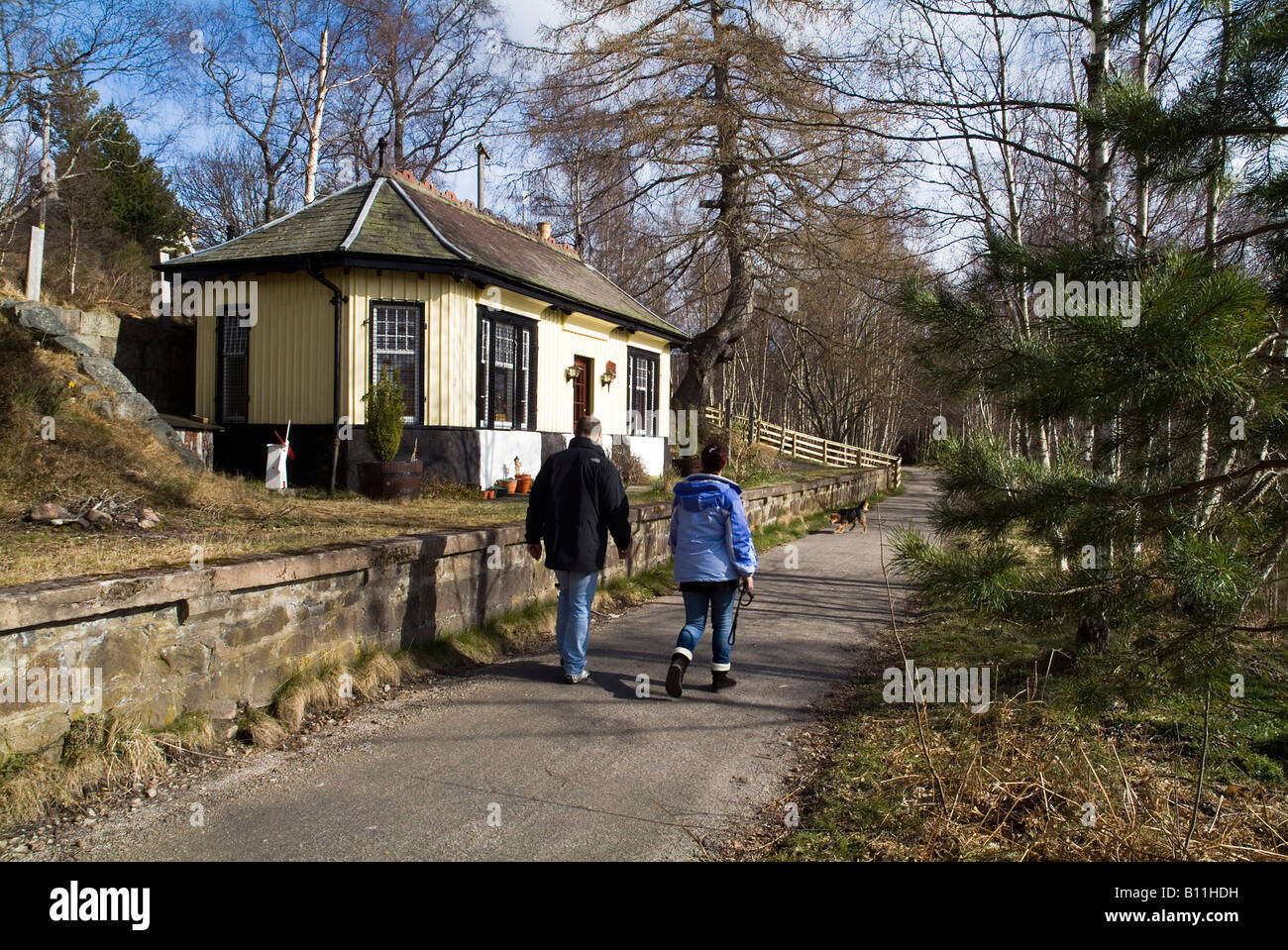 dh Cambus O May ROYAL DEESIDE ABERDEENSHIRE Couple walking on footpath past old railway line station people hikers in scotland hiking highland Stock Photo