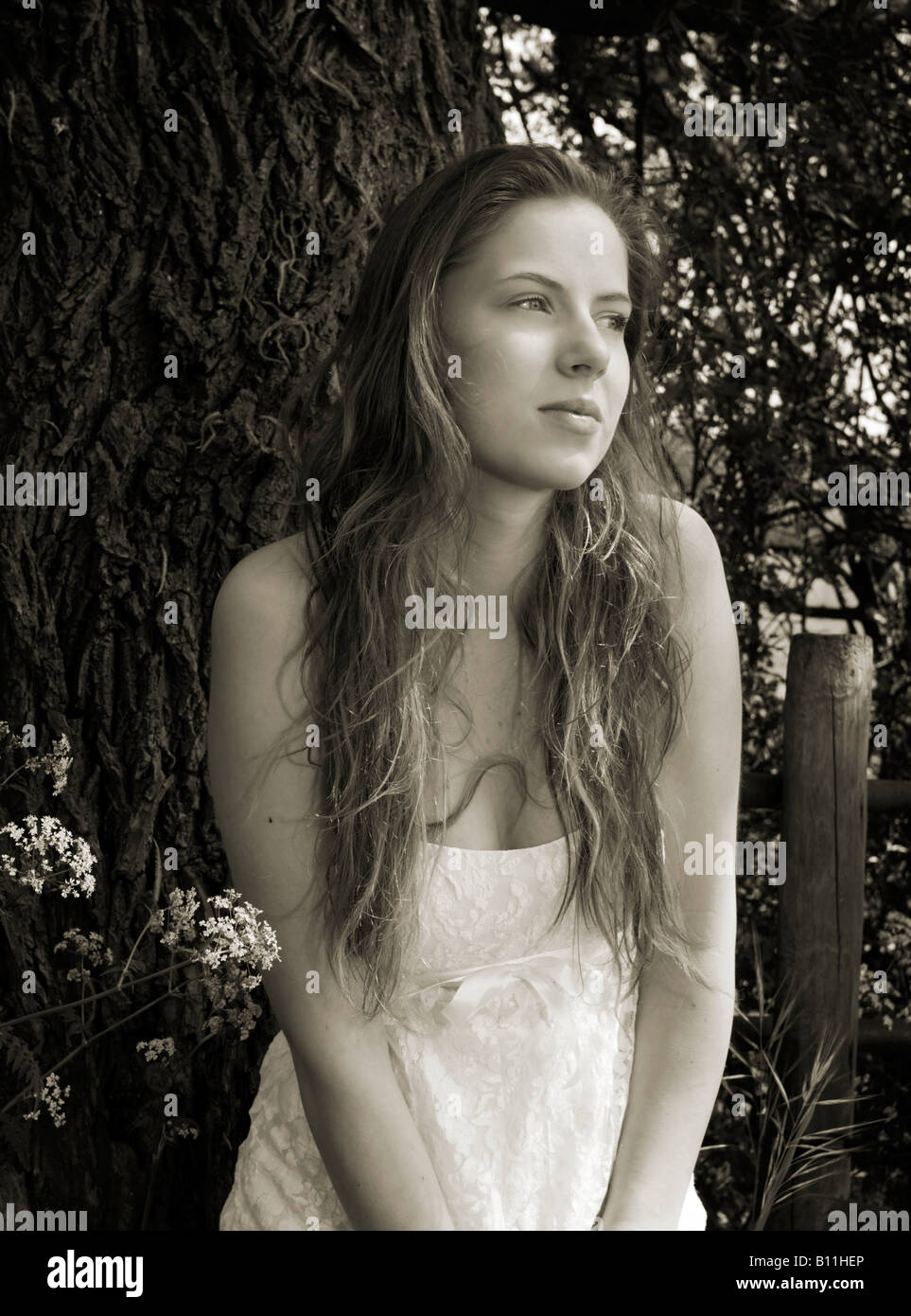 A teenage girl in a field wearing a white dress poses for the camera Stock Photo