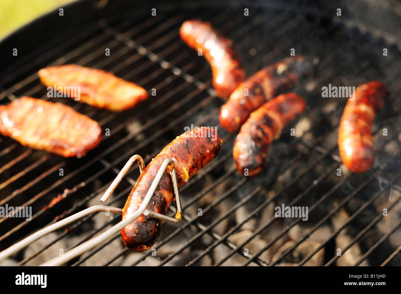 Grilling bratwursts and pork on a charcoal grill Stock Photo Alamy