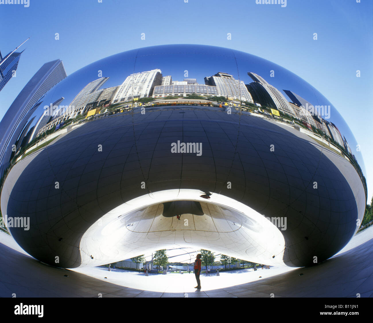 MAN STANDS UNDER CLOUD GATE MILLENNIUM PARK DOWNTOWN SKYLINE CHICAGO