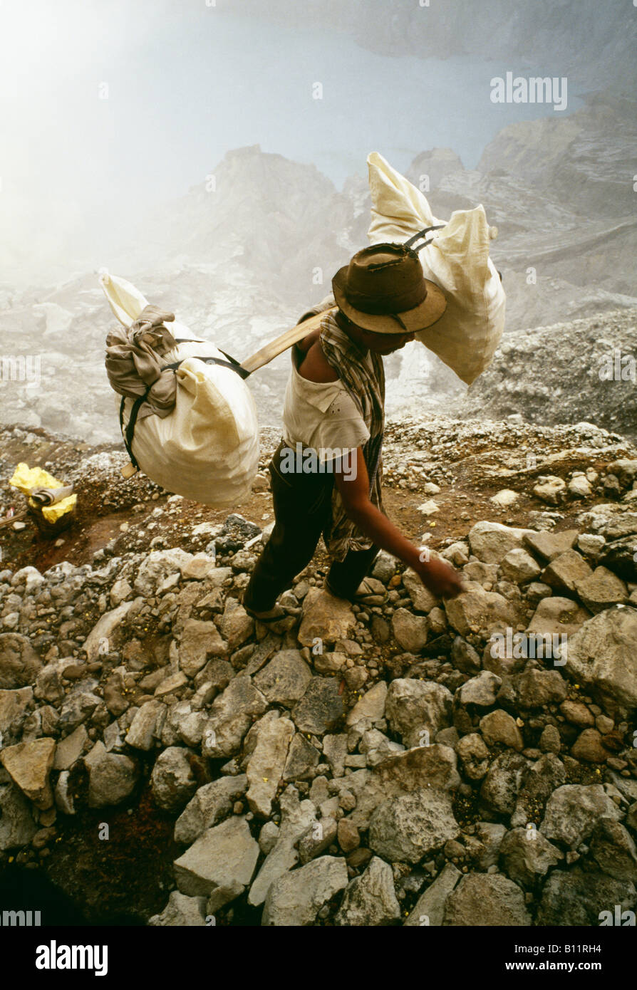 Miners carry baskets full of sulfur out of the volcano to collection point. Stock Photo