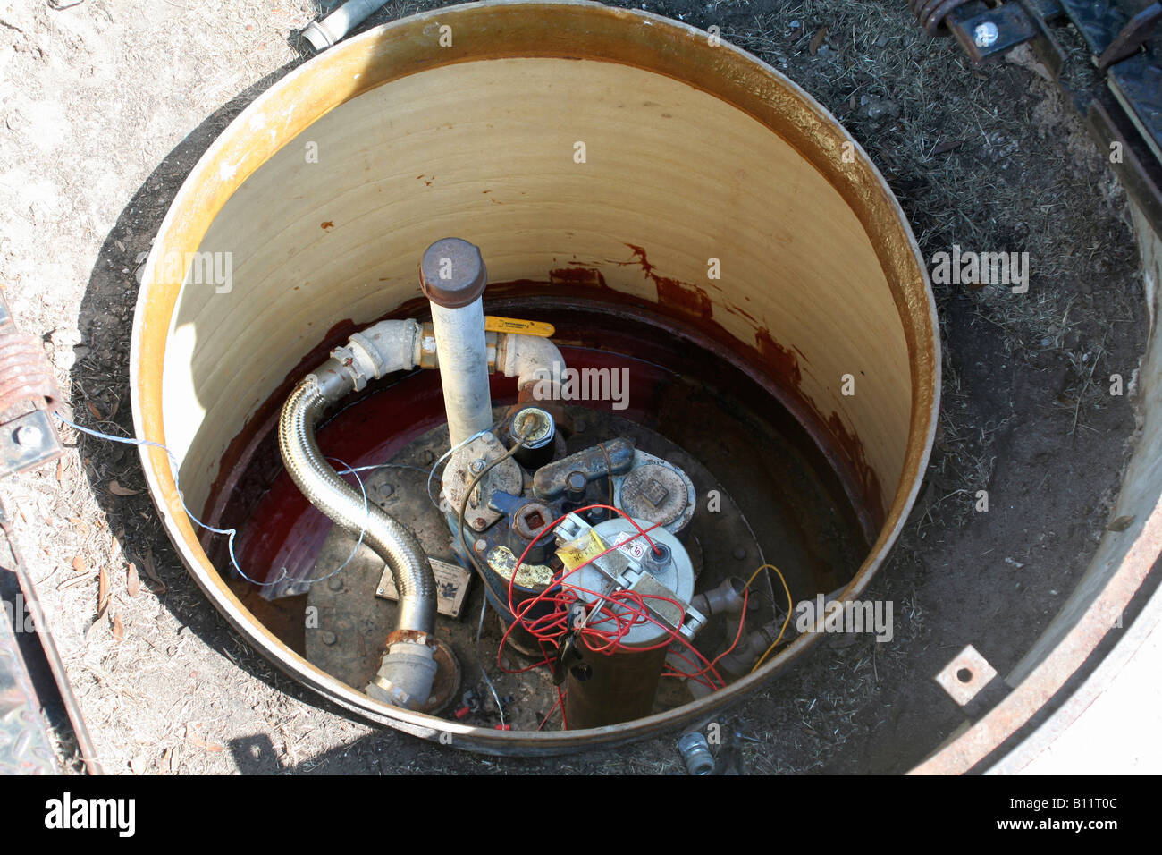 Well pit with well casing head and electrical connections Stock Photo